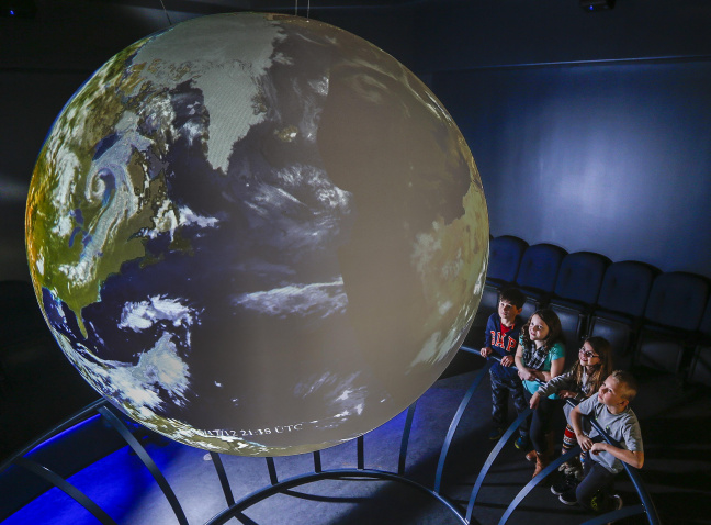 Four children looking at Earth projected on Science on a Sphere.